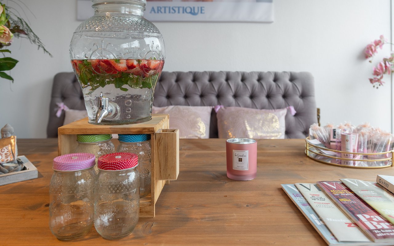 Tafel met een karaf water met fruit en roze kussens